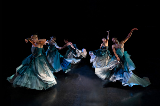 5 dancers in billowing teal gowns on stage.
